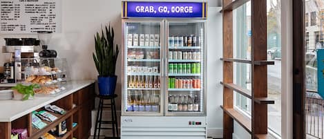 A cafe with a menu board, a beverage dispenser, and a variety of snacks and drinks.