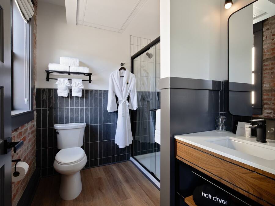 A modern bathroom with a toilet, a shower area, and a vanity with a mirror.