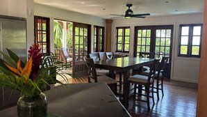 A dining area with a large table, chairs, and a ceiling fan.