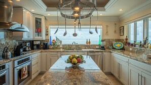 A modern kitchen with granite countertops, stainless steel appliances, and a central island with fruit.