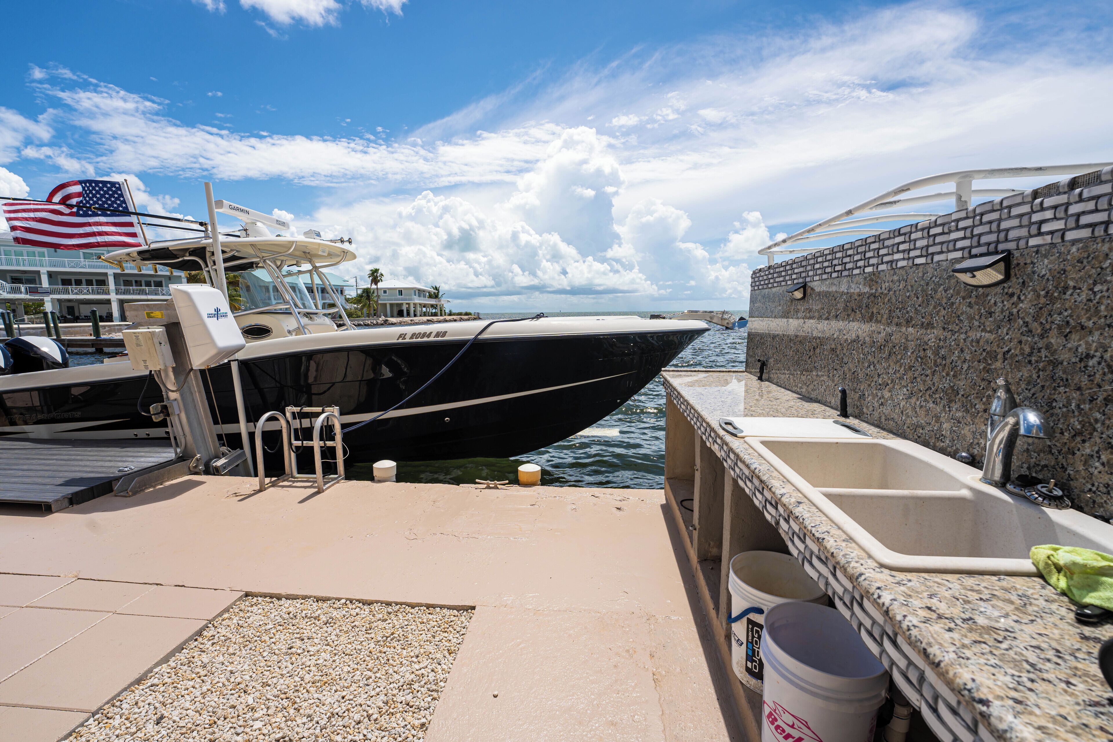 A boat docked at a marina with a view of the ocean and a house in the background.