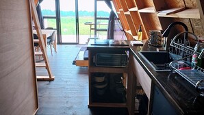 Een slaapkamer in loftstijl met een schuine plafond, een dakraam, een houten bureau, een magnetron en een wastafel.