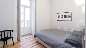 Een slaapkamer met een bed, een stoel en een deur naar een buitenruimte.
