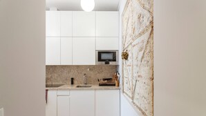 Een moderne keuken met witte kastjes, een magnetron en een spoelbak.