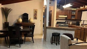 A spacious living area with a dining table and chairs, a kitchen with wooden cabinets, and a ceiling fan.