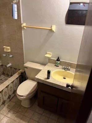 A small bathroom with a toilet, sink, and mirror. There is a towel rack above the sink and a soap dispenser on the counter. - Malibu low-rise house (Baja Malibú)