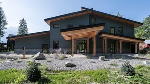 A modern two-story house with a covered patio area and a landscaped garden. - Camozzi Chalet by Revelstoke Vacations (Revelstoke)