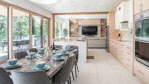 A modern kitchen with a central island, built-in appliances, and large windows. - Camozzi Chalet by Revelstoke Vacations (Revelstoke)
