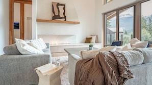 A modern living room with a sofa, coffee table, and a fireplace. - Camozzi Chalet by Revelstoke Vacations (Revelstoke)