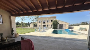 Un espacio al aire libre cubierto con piscina, sillas de descanso y una mesa de patio.