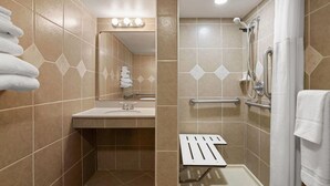 A bathroom with a sink, mirror, towel rack, shower with grab bars, and a toilet. - Tesla Biohealing Wellness Hotel & Resort, Ramada by Wyndham (Butler)