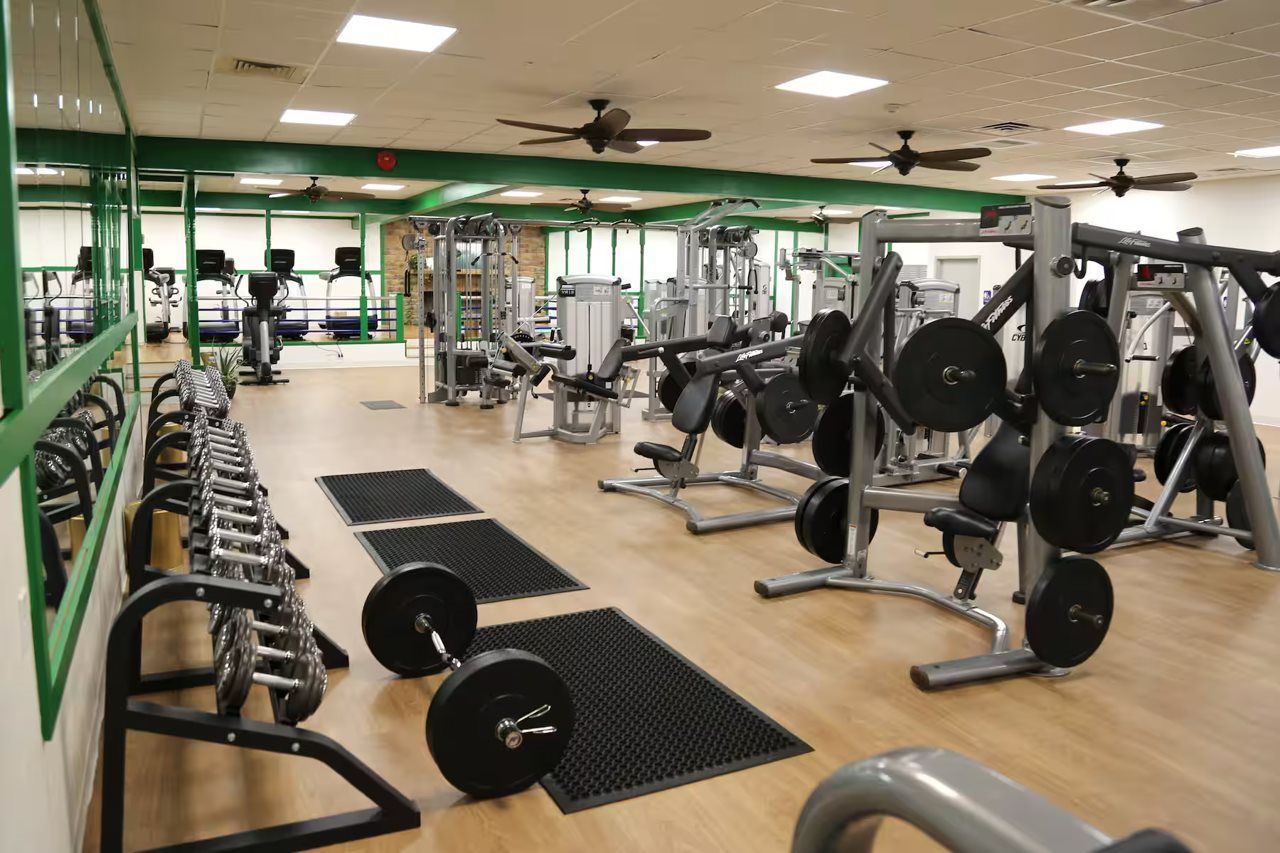A gym with various exercise equipment, including dumbbells, weight plates, and machines.
