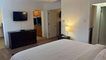 Une chambre d’hôtel comprenant un lit, un téléviseur fixé au mur, une commode et une porte donnant accès à une salle de bain.