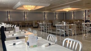 A hotel dining area with marble tables, white chairs, and chandeliers. - Tesla Biohealing Wellness Hotel & Resort, Ramada by Wyndham (Butler)