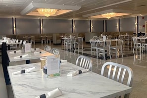 A hotel dining area with marble tables, white chairs, and chandeliers. - Tesla Biohealing Wellness Hotel & Resort, Ramada by Wyndham (Butler)