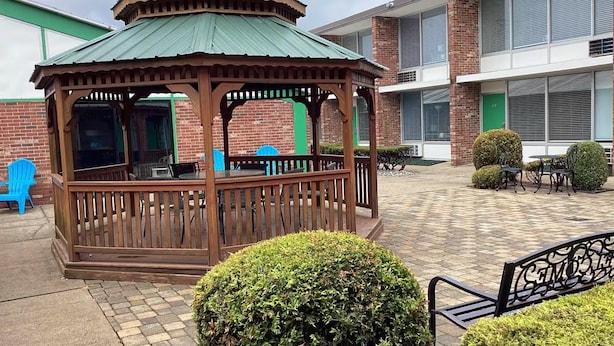 A gazebo with a green roof, a brick building in the background, and a paved patio area. - Tesla Biohealing Wellness Hotel & Resort, Ramada by Wyndham (Butler)