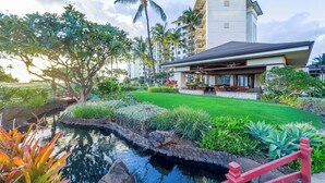 A resort with a pool, palm trees, and a building with a flat roof.