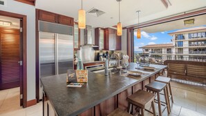 A modern kitchen with a large island, stainless steel appliances, and pendant lighting.