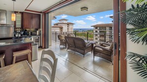 A modern kitchen with a dining area and a balcony overlooking a scenic view.