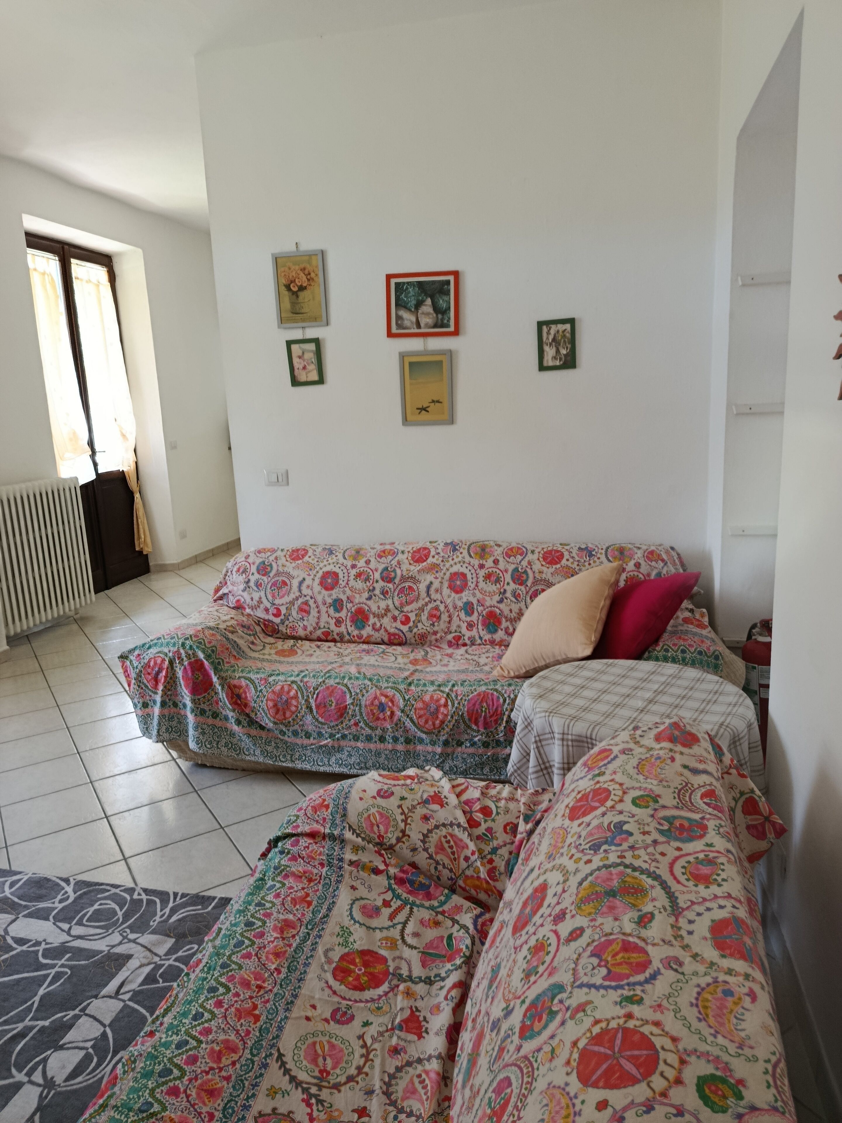 A room with a sofa bed, a radiator, and a window with curtains.