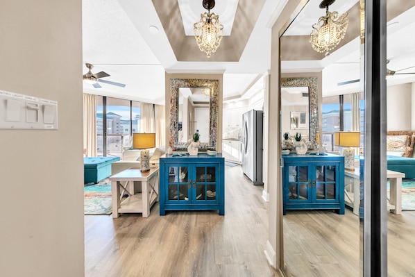 A spacious living room with a blue cabinet, a chandelier, and a large mirror.