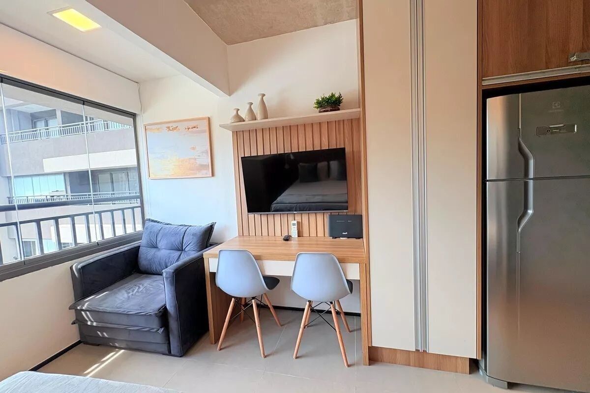 A compact living space with a kitchenette, a sofa, two chairs, a TV, and a refrigerator.