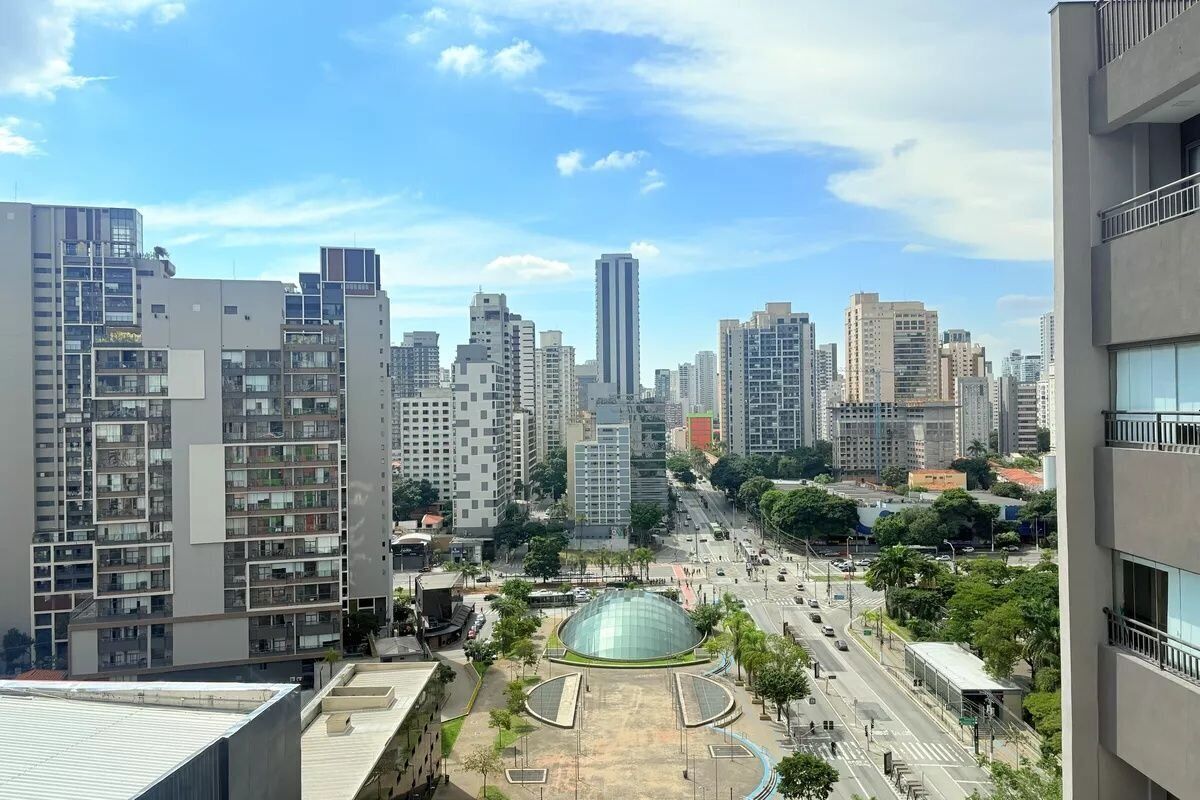 A high-rise urban area with modern buildings, a central roundabout, and a clear sky.