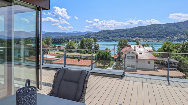 A balcony with a view of a lake, mountains, and houses.
