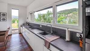 A modern kitchen with a large window, a sink, and a countertop.