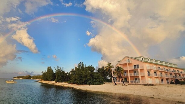 Een hotel aan het strand met een zwembad, een strand en een regenboog.