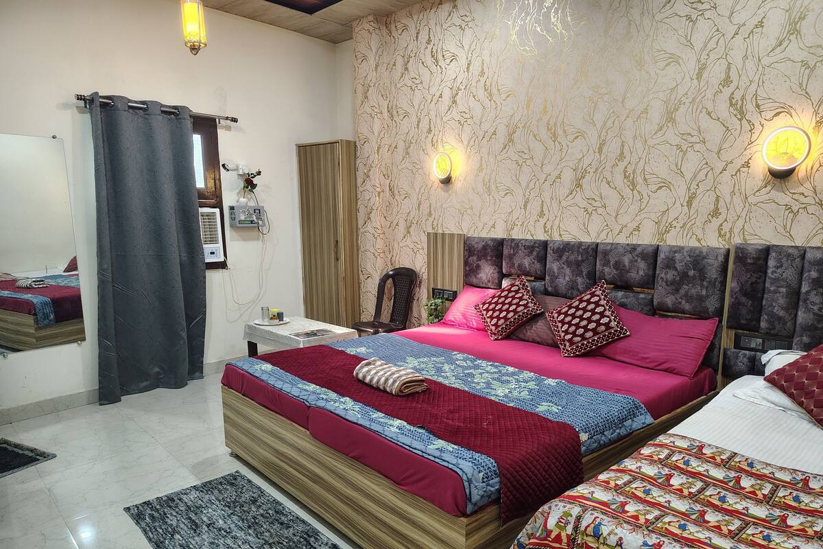 A bedroom with a large bed, a bedside table, a mirror, a wall-mounted air conditioner, and patterned wallpaper.