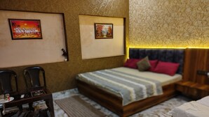 Camera da letto con un letto, due quadri incorniciati, un comodino, una testiera in legno e una borsa nera.