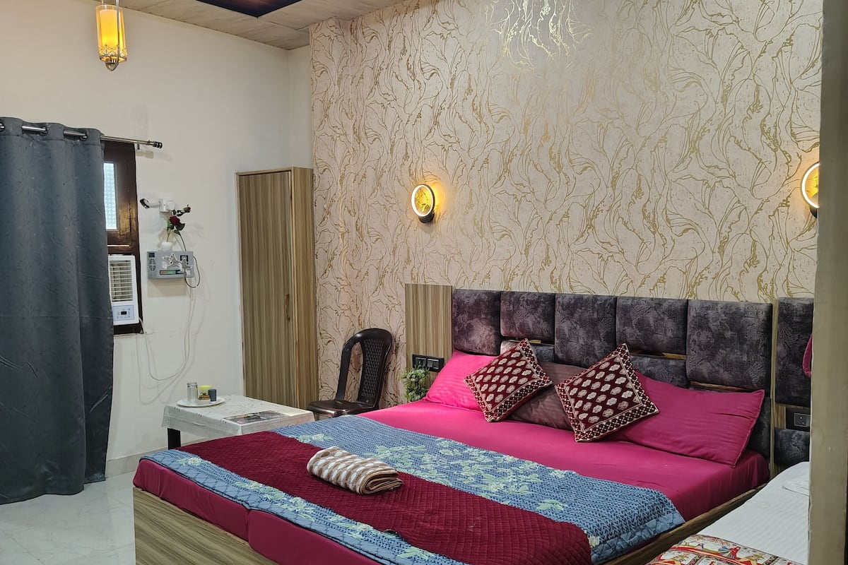 A bedroom with a large bed, a smaller bed, a ceiling fan, and a wall-mounted light fixture.