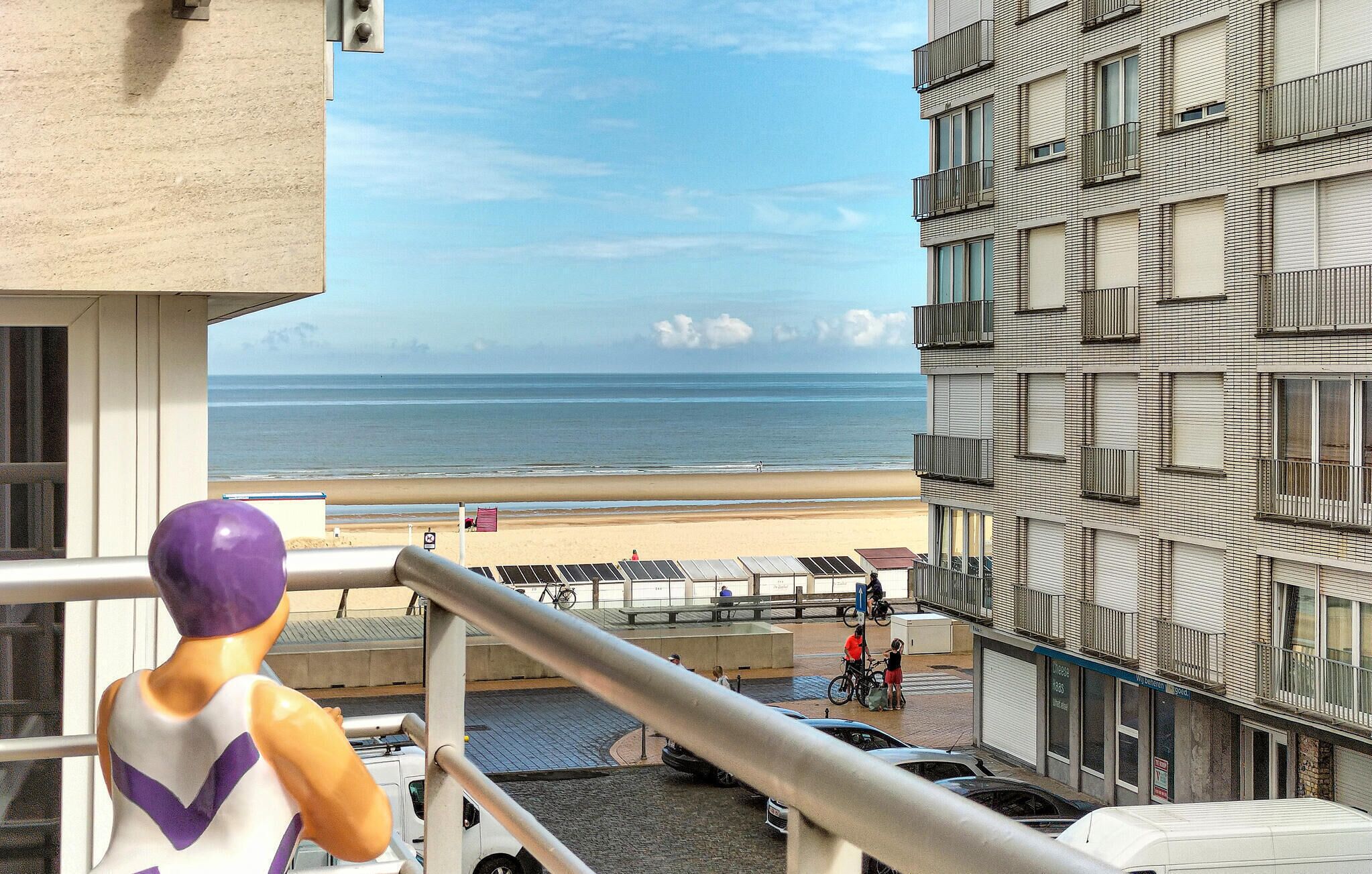 A view of a beach from a balcony with a statue in the foreground.