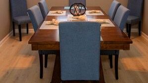 Une salle à manger avec une table en bois, six chaises bleues et un lustre.
