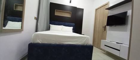 Un dormitorio con cama, televisor montado en la pared y armario.