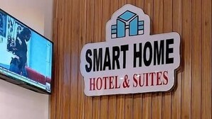 A reception area with a sign reading "SMART HOME HOTEL & SUITES" and a television mounted on the wall. - Smart Home Hotel Lagos (Lekki)