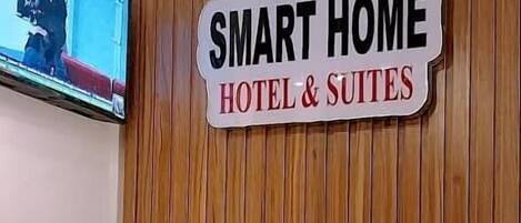 Una recepción con un letrero que dice 'SMART HOME HOTEL & SUITES' y un televisor montado en la pared.