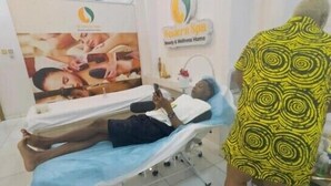 A medical examination room with a bed, a patient lying on it, and a healthcare professional standing beside. - Smart Home Hotel Lagos (Lekki)