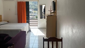 Ein Hotelzimmer mit Bett, Schreibtisch, Stuhl, Klimaanlage und Fernseher.