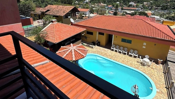 Ein Hotel mit Schwimmbad, roten Ziegeldächern und Blick auf eine Hügelstadt.