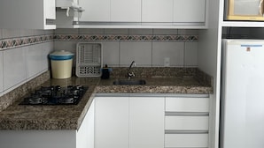 Eine Küche mit weißen Schränken, einer Arbeitsplatte aus Granit, einer Mikrowelle, einem Spülbecken und einem Kühlschrank.
