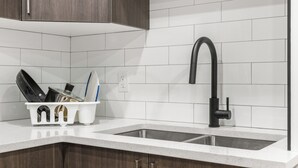 A kitchen with two sinks, wooden cabinets, and a white tiled backsplash. - Lake Community Hideout (Chestermere)