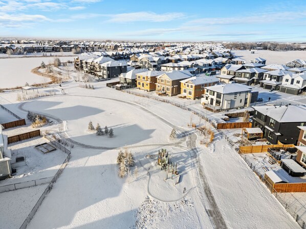 A residential area with multiple houses, a snow-covered landscape, and a clear sky. - Lake Community Hideout (Chestermere)