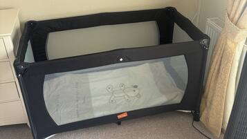 A room with a black baby playpen, a television on the wall, and a radiator.