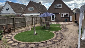 Un jardin avec un espace patio, un barbecue et une clôture en bois.