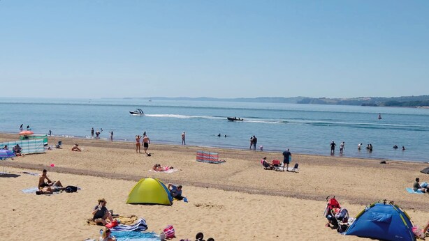 Une plage avec des tentes, des parasols et des gens qui profitent de l’eau.