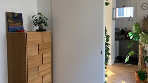 A modern room with a wooden wardrobe, a bed, a painting, and a potted plant.