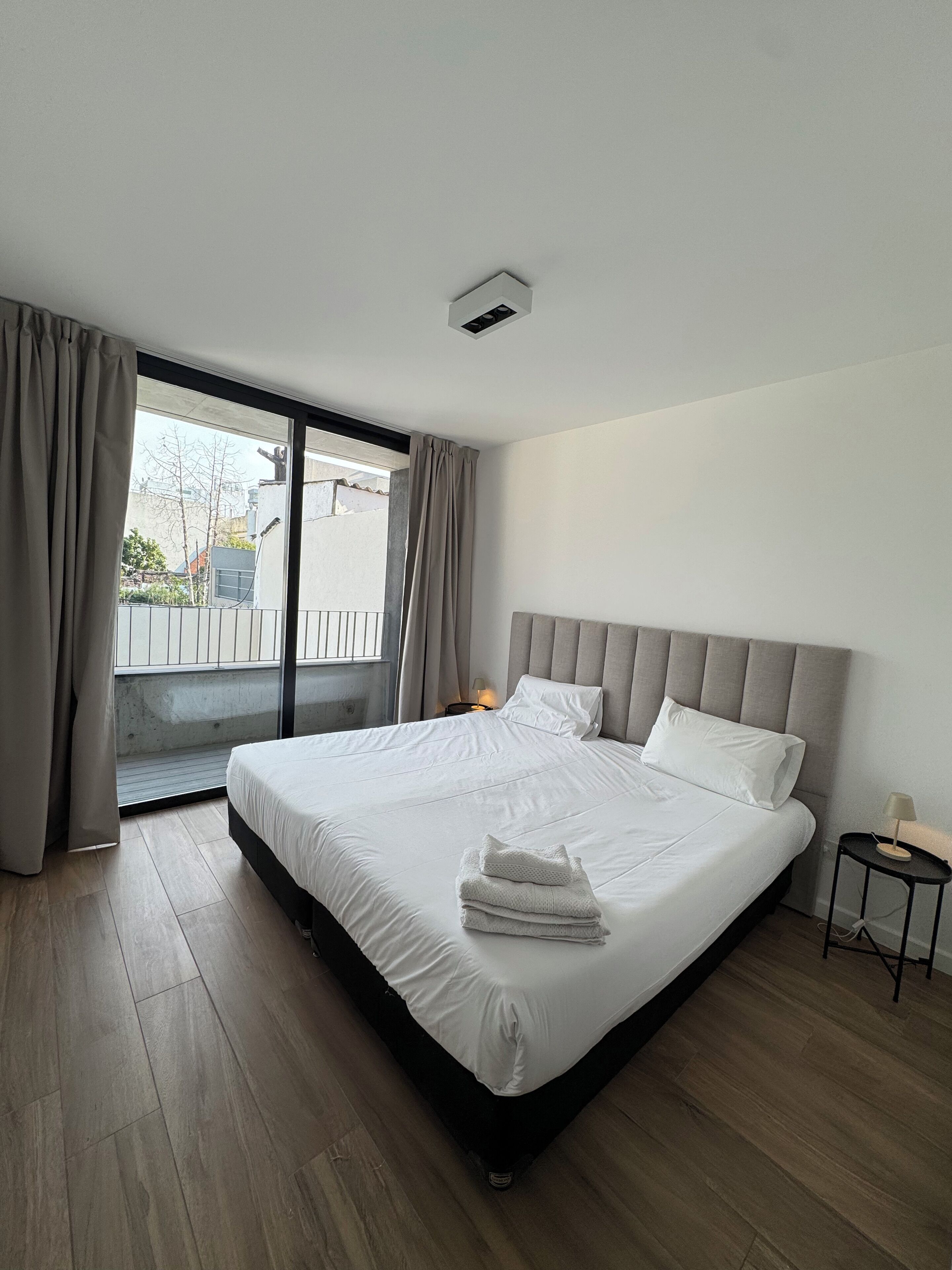 Camera d'albergo moderna con un grande letto, un comodino e vista all'esterno tramite una porta scorrevole.