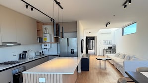 Una cocina moderna con una isla central, electrodomésticos de acero inoxidable y suelo de madera.